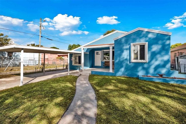 4711 NW 11th Ave, Miami, FL 33127 - view of front of property with fence, an attached carport, a front lawn, stucco siding, and a porch