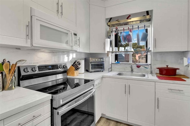 4711 NW 11th Ave, Miami, FL 33127 - kitchen featuring white cabinets, stainless steel electric range oven, tasteful backsplash, a sink, and white microwave