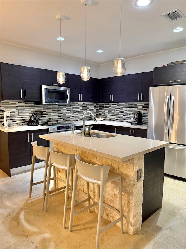 kitchen featuring stainless steel appliances, light countertops, and a center island with sink