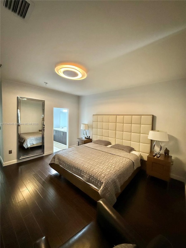bedroom featuring dark wood-style flooring, connected bathroom, visible vents, and baseboards