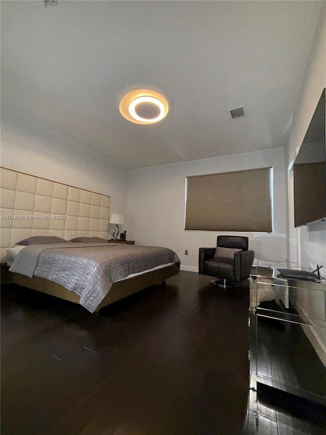 bedroom featuring visible vents, baseboards, and wood finished floors