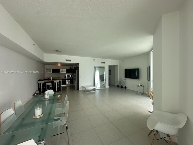 living room featuring visible vents, a textured ceiling, and light tile patterned floors