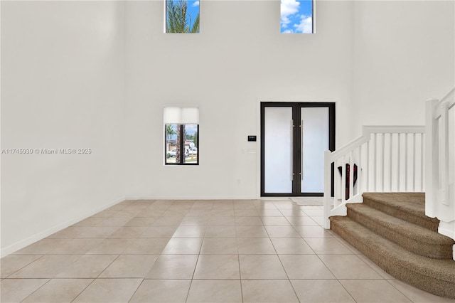 foyer with baseboards, stairway, light tile patterned floors, french doors, and a high ceiling