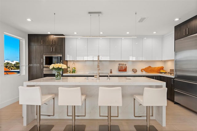350 Desoto St, Hollywood, FL 33019 - kitchen with built in appliances, dark brown cabinets, a kitchen breakfast bar, pendant lighting, and a kitchen island with sink