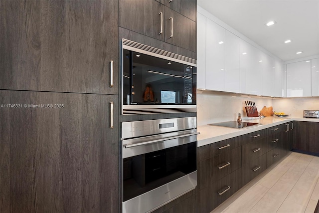 350 Desoto St, Hollywood, FL 33019 - kitchen with built in microwave, white cabinetry, backsplash, stainless steel oven, and black electric cooktop