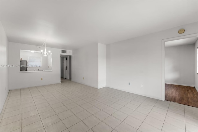 tiled empty room with a notable chandelier