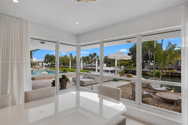 sunroom featuring a water view