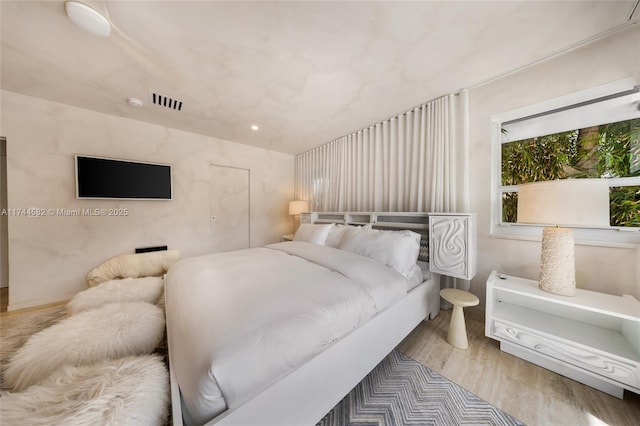 bedroom with light wood finished floors and visible vents