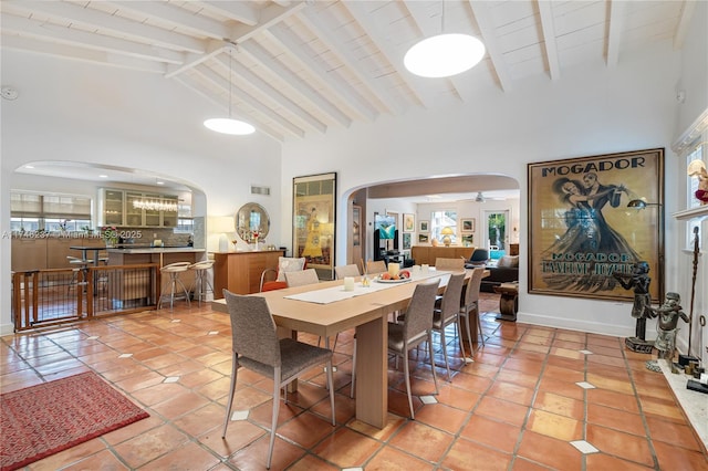 tiled dining space featuring high vaulted ceiling, ceiling fan, and beam ceiling