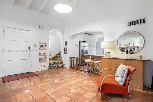 entryway with beam ceiling, high vaulted ceiling, and light tile patterned flooring