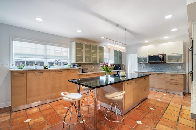 kitchen with light tile patterned floors, a kitchen island, light brown cabinets, a breakfast bar area, and tasteful backsplash