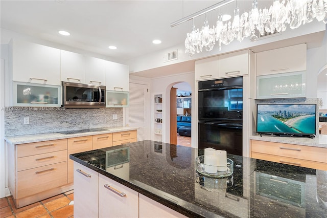 kitchen with pendant lighting, dark stone counters, black appliances, white cabinets, and tasteful backsplash