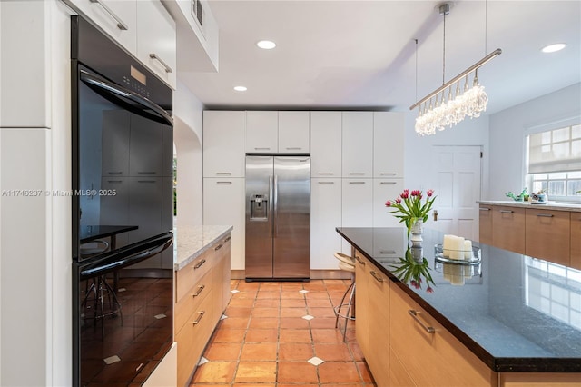 kitchen featuring black double oven, white cabinets, stainless steel fridge, a kitchen island, and dark stone countertops