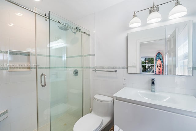 bathroom with tile walls, an enclosed shower, vanity, and toilet