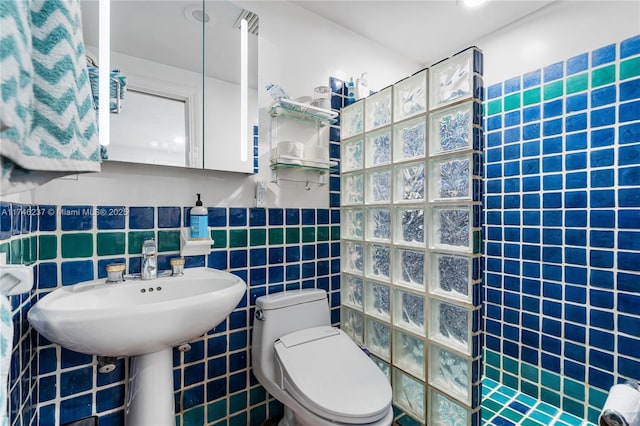 bathroom featuring tiled shower, tile walls, and toilet