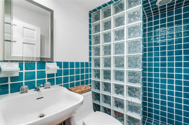 bathroom featuring tile walls, sink, toilet, and walk in shower