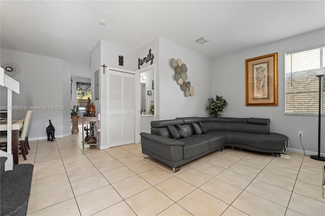 living room featuring light tile patterned flooring, visible vents, and baseboards