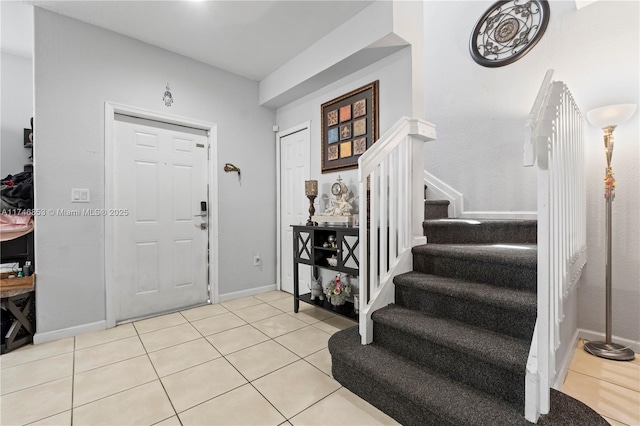 entrance foyer featuring baseboards, stairway, and tile patterned floors