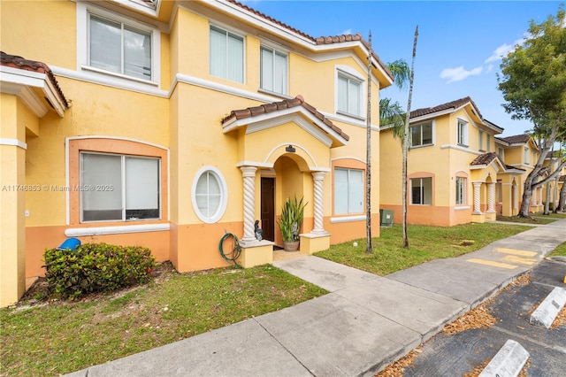 multi unit property featuring a front lawn, a tile roof, a residential view, and stucco siding