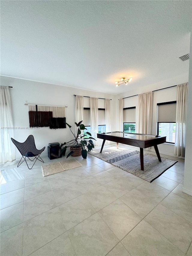 game room with a textured ceiling and light tile patterned flooring