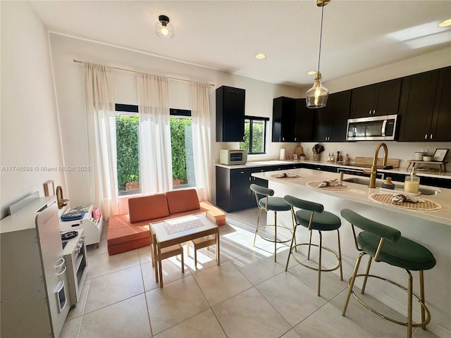 kitchen featuring sink, light tile patterned floors, a kitchen breakfast bar, and decorative light fixtures