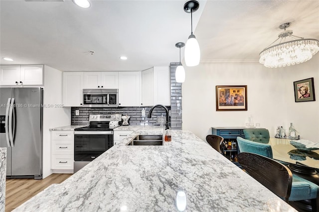 kitchen with stainless steel appliances, white cabinetry, sink, and pendant lighting