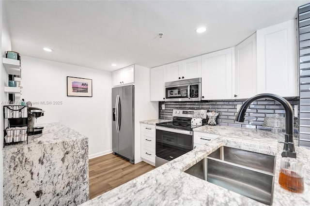 kitchen with white cabinetry, stainless steel appliances, light stone countertops, and sink