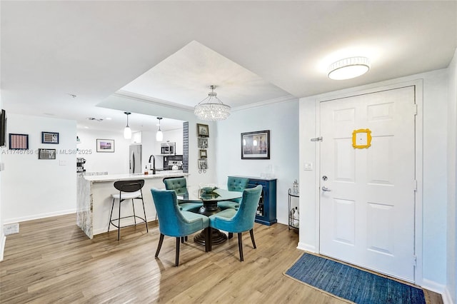 dining area featuring sink, a notable chandelier, and light hardwood / wood-style floors