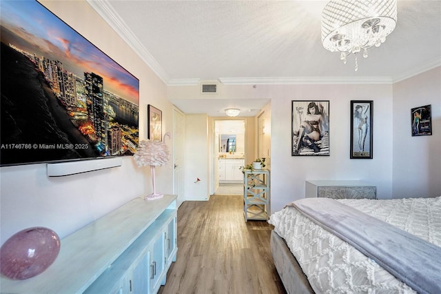 bedroom with crown molding, ensuite bathroom, light hardwood / wood-style floors, a textured ceiling, and a chandelier