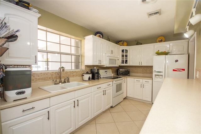 kitchen with white appliances, tasteful backsplash, white cabinetry, a sink, and light tile patterned flooring