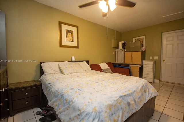 bedroom featuring light tile patterned floors, attic access, and a ceiling fan