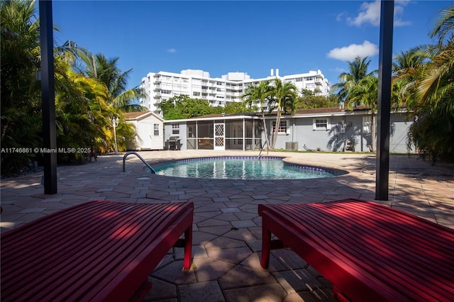 pool featuring a sunroom and a patio area