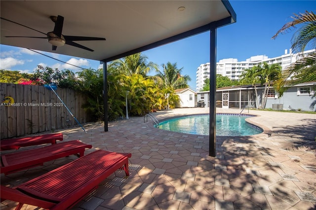 view of swimming pool featuring ceiling fan, a patio, an outdoor structure, fence, and a fenced in pool