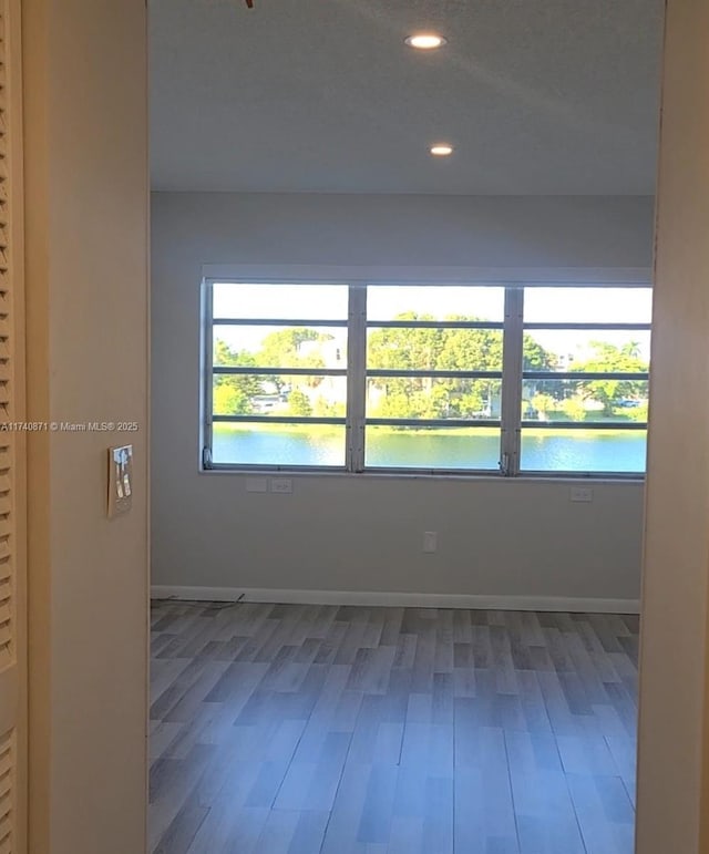 spare room with hardwood / wood-style flooring and a water view