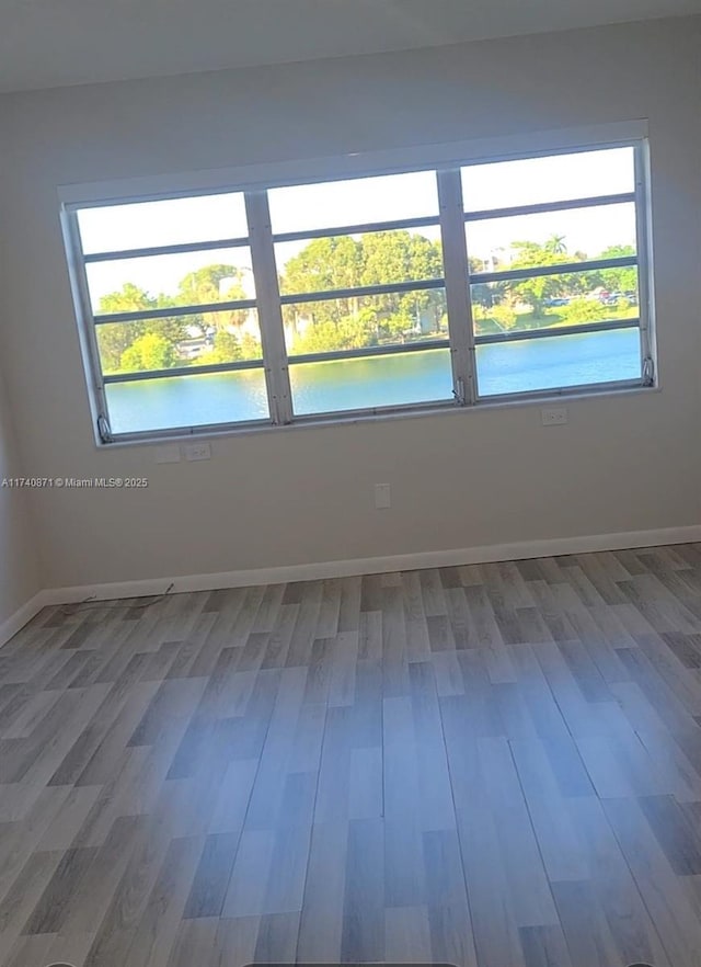 spare room with hardwood / wood-style flooring, a wealth of natural light, and a water view