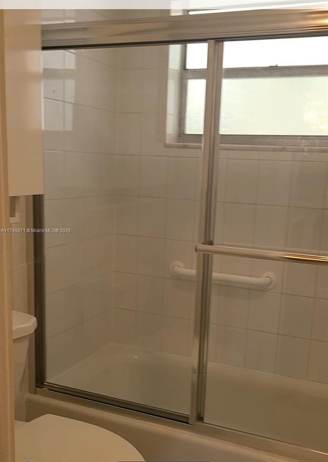 bathroom with enclosed tub / shower combo and toilet