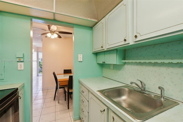 kitchen with tasteful backsplash, white cabinetry, sink, black electric range oven, and light tile patterned floors