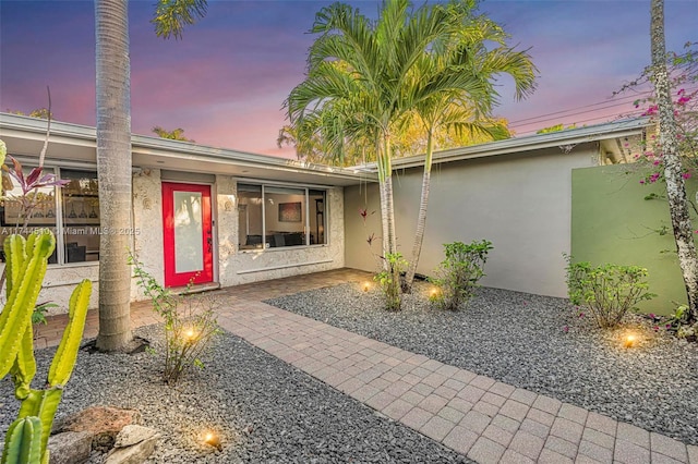 exterior entry at dusk featuring a patio