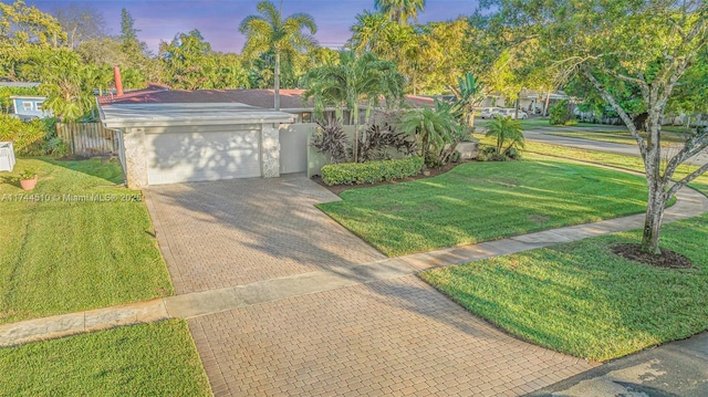 ranch-style house featuring a garage and a yard