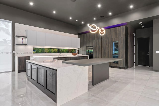 kitchen with a large island, a high ceiling, white cabinets, a kitchen bar, and decorative backsplash