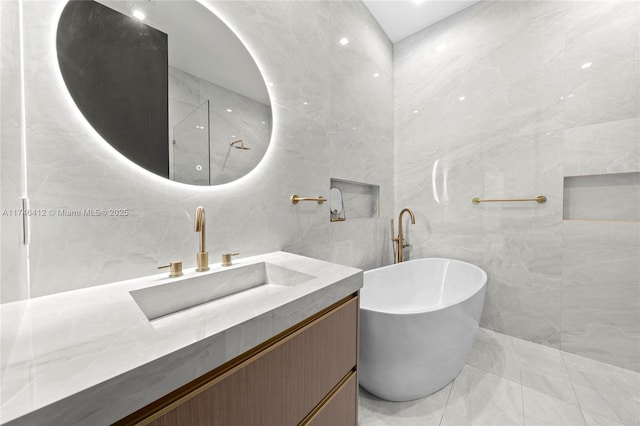 bathroom with vanity, a tub, and tile walls