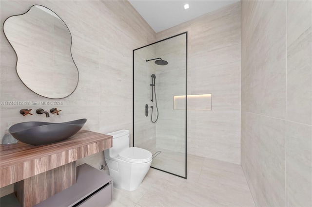 bathroom featuring vanity, toilet, tile walls, and a tile shower