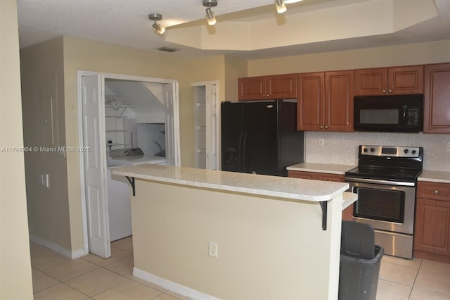 kitchen featuring light tile patterned flooring, a kitchen breakfast bar, a textured ceiling, and black appliances