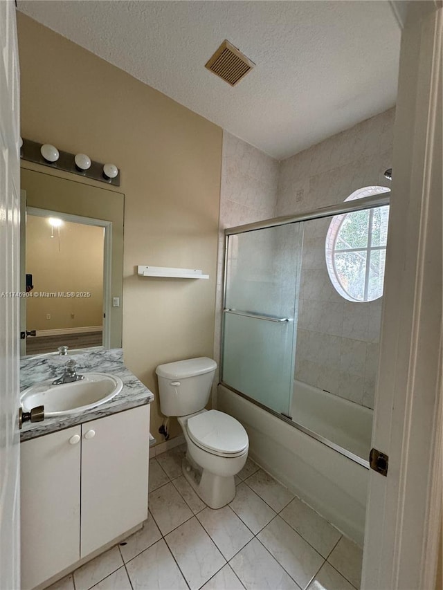 full bathroom featuring tile patterned floors, toilet, bath / shower combo with glass door, a textured ceiling, and vanity