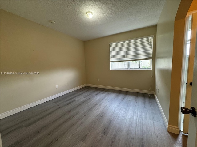 empty room with dark wood-type flooring and a textured ceiling