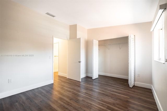 unfurnished bedroom with dark hardwood / wood-style floors and a closet