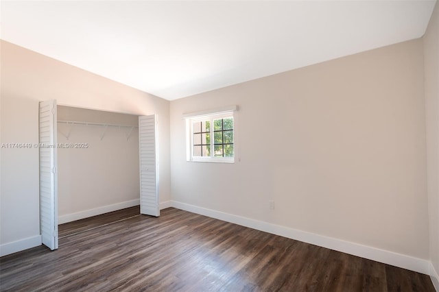 unfurnished bedroom featuring lofted ceiling, dark hardwood / wood-style flooring, and a closet