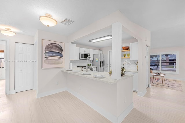 kitchen featuring white cabinetry, backsplash, stainless steel appliances, and kitchen peninsula