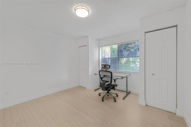 unfurnished office featuring a textured ceiling and light wood-type flooring