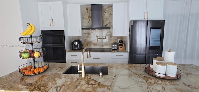 kitchen with white cabinets, wall chimney exhaust hood, a sink, black appliances, and backsplash